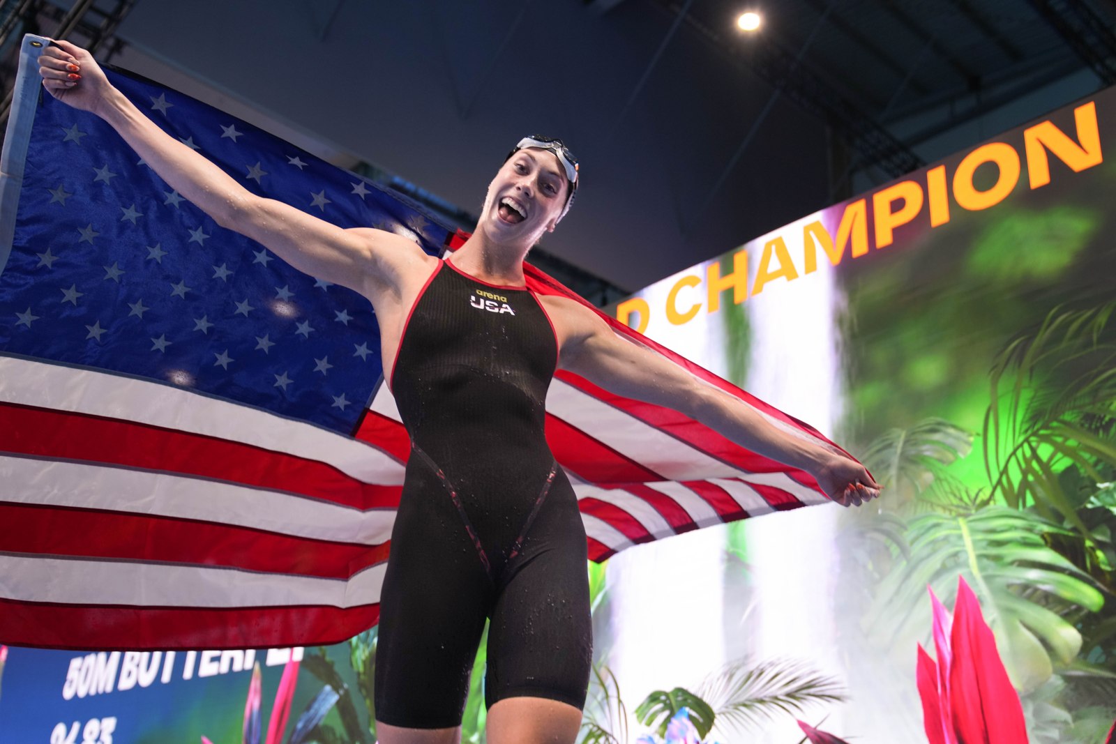 Gretchen Walsh looks into the camera while holding an American flag out behind her.